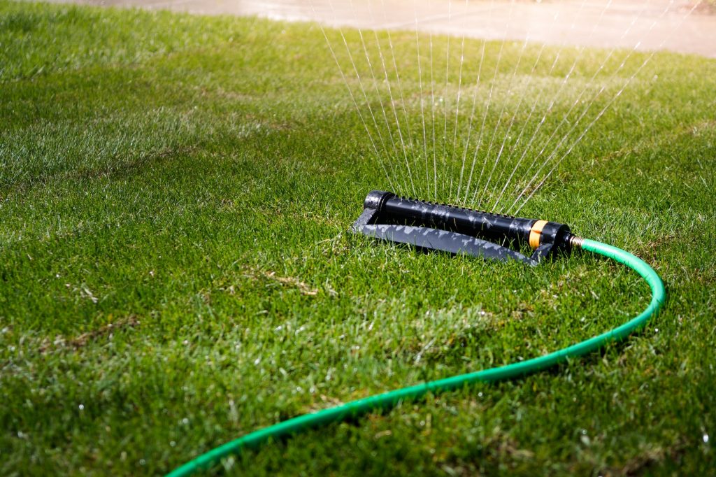 Water sprinkler spraying water on green grass lawn